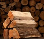 Pile of hickory firewood against a larger stack, showcasing a face cord of wood.