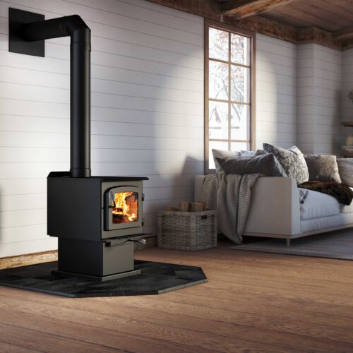 Modern wood stove in a cozy cabin interior with a bed near a window.