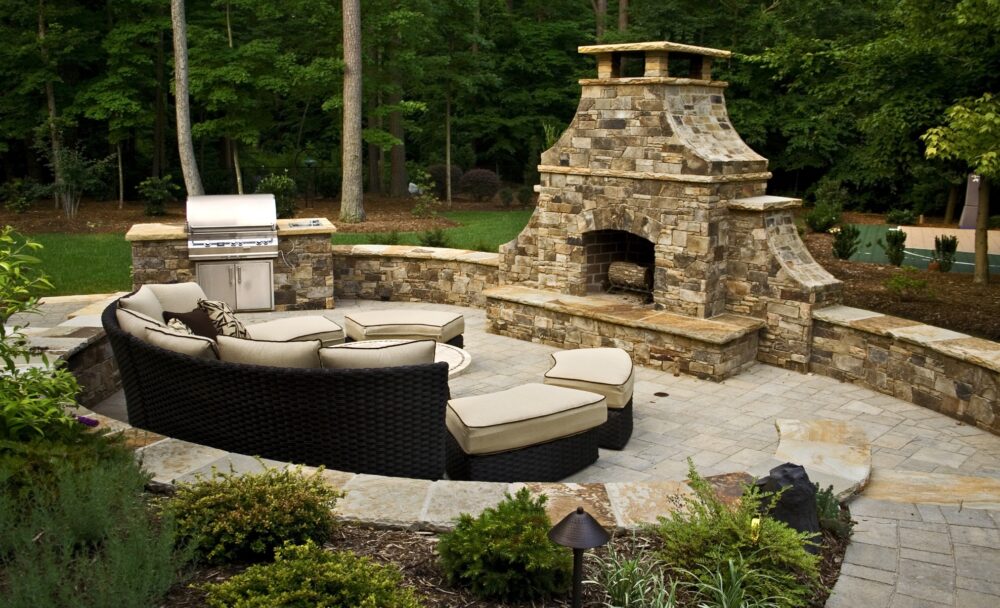 Beautiful arched outdoor stone fireplace on a backyard patio.