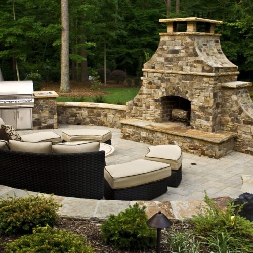 Beautiful arched outdoor stone fireplace on a backyard patio.