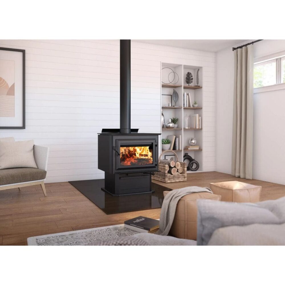 A cozy living room featuring a black wood stove on a hearth, with a fire burning inside. The room includes a sofa, an armchair, a rug, and shelves with decorative items.