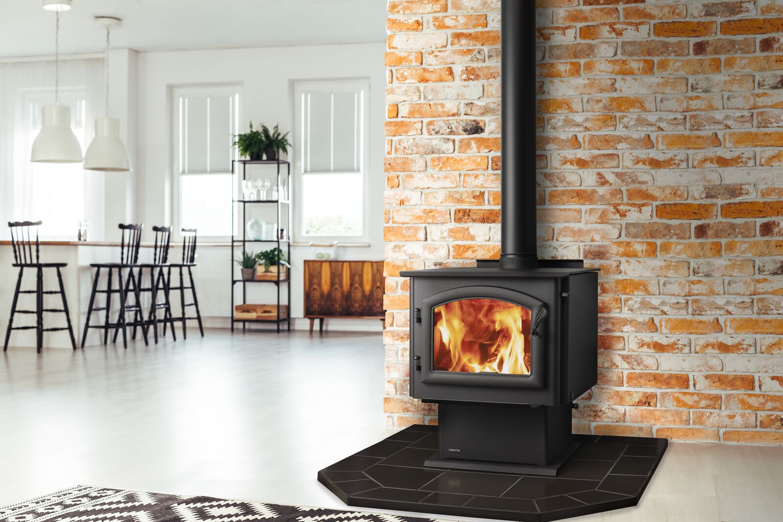 A modern wood-burning stove set against a brick wall in a bright, open-concept living area with contemporary furniture and decor.