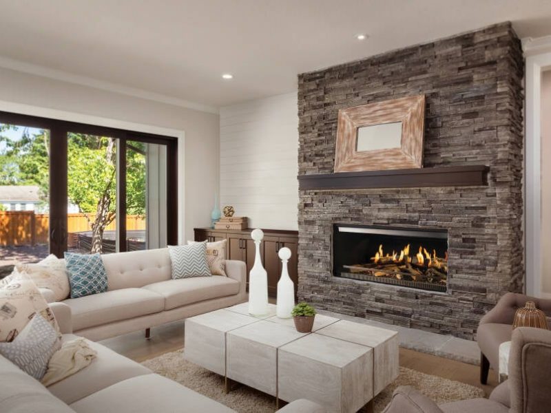 The NetZero E-One fireplace in a modern living room with a stone fireplace surround.